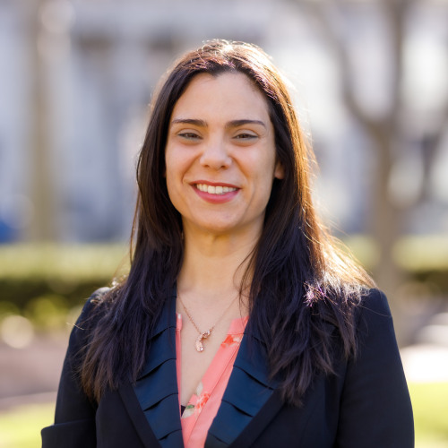 Headshot of Dr. Argie Veroniki smiling outdoors, wearing a black blazer over a peach floral blouse